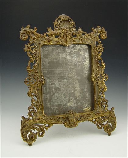 BRADLEY & HUBBARD CAST IRON PETTICOAT MIRROR FRAME: BRADLEY & HUBBARD PETTICOAT MIRROR FRAME: Foliate scroll with masqueron, marked on back B & H 3565, no mirror. 17" x 13 1/4".