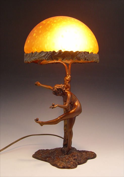 VINTAGE NUDE FIGURAL LAMP: VINTAGE NUDE FIGURAL LAMP: Figure of nude woman balancing fruit on hands and foot. Signed S. Hestnertec? on base. Spotted orange glass shade. Base measures 12" h. x 8" x 6", shade 4 3/4" x 8" dia.