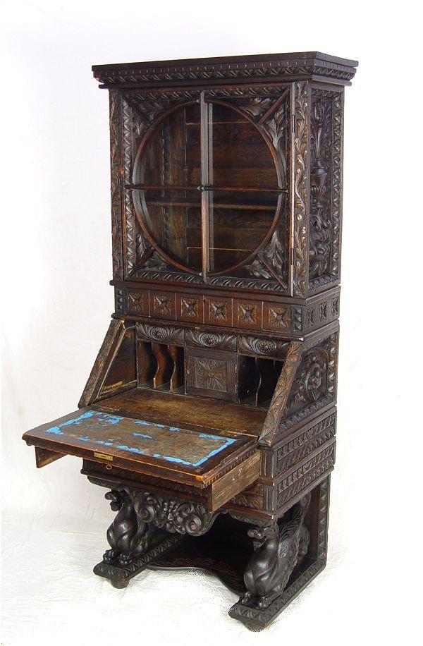 LAVISHLY CARVED BLACK FOREST SECRETARY DESK: LAVISHLY CARVED BLACK FOREST SECRETARY DESK: Two part. The top section with glass porthole design over lockable divided chamber. Below is a drop front desk with slotted interior and single door safe a