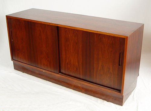 DANISH MODERN ROSEWOOD CREDENZA: DANISH MODERN ROSEWOOD CREDENZA: Double sliding doors. The interior with adjustable shelves and a pull out serving tray. Danish Control Stamp. Used condition. 26 1/2'' x 24 1/2'' x 17''.
