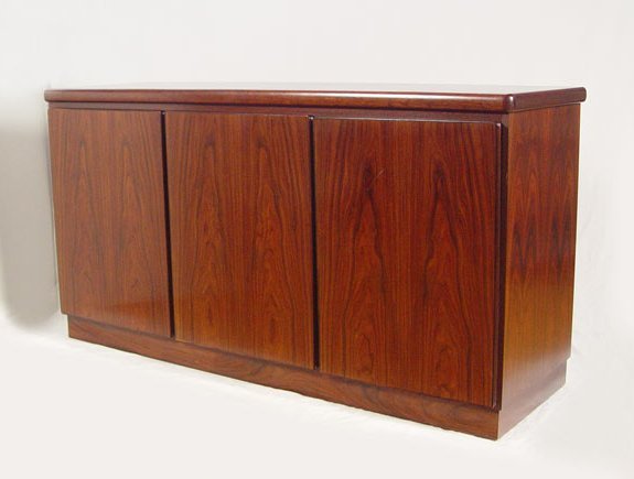 RASMUS DANISH MODERN ROSEWOOD CREDENZA: RASMUS DANISH MODERN ROSEWOOD VENEER CREDENZA: Three door sideboard. Adjustable interior shelves behind two doors, the other has felt lined pull out trays or drawers. 32" h. x 31 1/2" x 19".