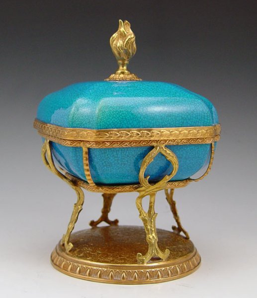 ORMOLU MOUNTED BOCH FRERES COVERED JAR: ORMOLU MOUNTED BOCH FRERES COVERED JAR: Flame finial covered box, blue crackle glaze and detailed brass lip. The ornate metal mounting is stamped "France", the ceramic bears the black Boch mark. Remov