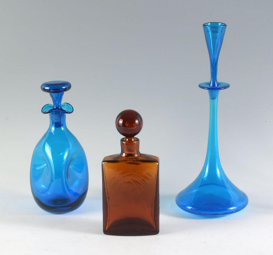 3 PC. MID-CENTURY BLENKO ART GLASS COLLECTION: 3 PC. MID-CENTURY BLENKO ART GLASS COLLECTION: Comprising; 1- tall blue decanter, 1- Pinched blue decanter, & 1- Amber colored decanter. Largest Approx. 15.5'' h x 6'' w.