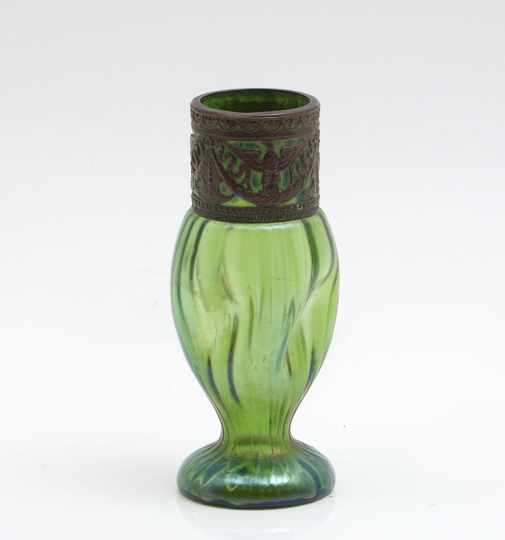 METAL MOUNTED LOETZ? VASE: METAL MOUNTED LOETZ? VASE: Green pinched glass vase, having a ribbed design. Copper mounted neck has an openwork Eagle, ribbon, & a draped foliate design. Approx. 6" h x 2.5" w.