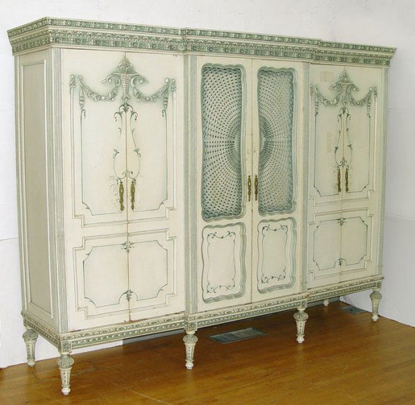 TRIPLE FRONT SHABBY ELEGANT FRENCH ARMOIRE: TRIPLE FRONT SHABBY ELEGANT FRENCH ARMOIRE: Three series of double doors, interior designed for shelves and rods. Painted finish, applied flower basket and swags. Center doors with caned front. Heavil