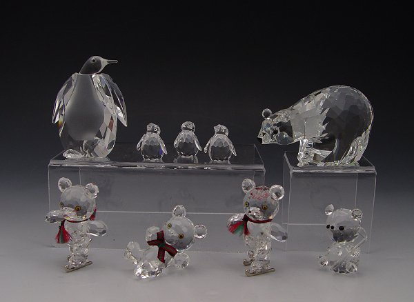 SWAROVSKI CRYSTAL POLAR BEAR KRIS BEARS & PENGUINS: SWAROVSKI CRYSTAL KINGDOM OF ICE AND SNOW: 1986 Large Polar Bear, Adi Stocker designer, retired 1997, approx. 3 1/2''l.; Large Penguin by Zoo, approx. 2 1/2''h. watches over the 1997 Three Baby Pengui