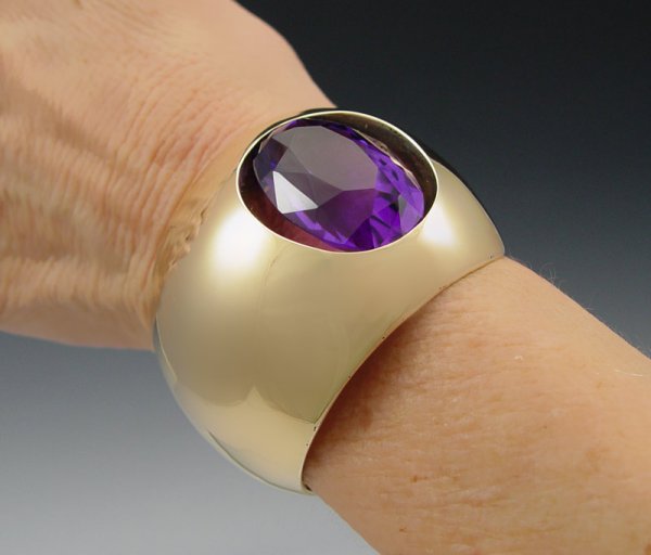 ANTONIO PINEDA 14k GOLD AMETHYST CUFF BRACELET: ANTONIO PINEDA 14K GOLD AMETHYST CUFF BRACELET: 14K yellow gold cuff bracelet contains one oval shaped mixed cut amethyst. Weight: 50.00 Ct. Approx. The amethyst is channel set. Gold Weight: 68.5 gram