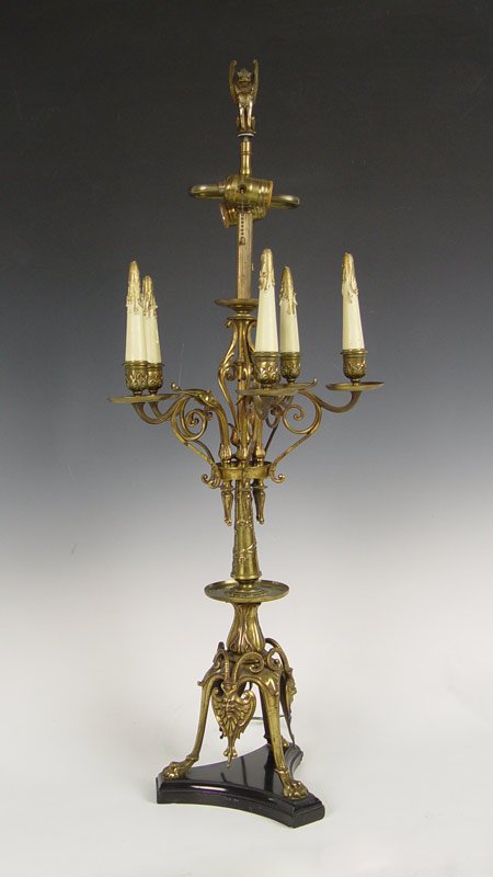 BRONZE TABLE TOP CANDELABRA LAMP: BRONZE TABLE TOP CANDELABRA LAMP: Tri legged paw foot base with horned masquerons, five arm candle holder centered by an electric lamp, winged griffin finial, 36"h., approx. 14" dia. arm to arm.