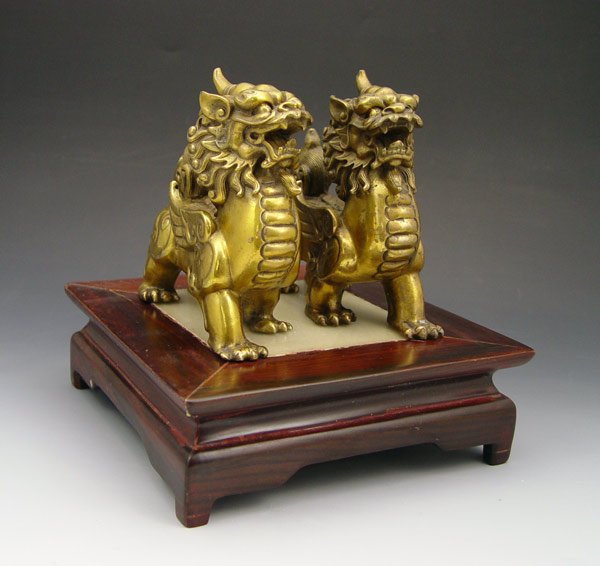 PAIR CHINESE MYTHOLOGICAL BEASTS: PAIR CHINESE MYTHOLOGICAL BEASTS: Good brass figures, accompanied by a stone and wood stand. 4 1/2"h. x 4 1/2"l.