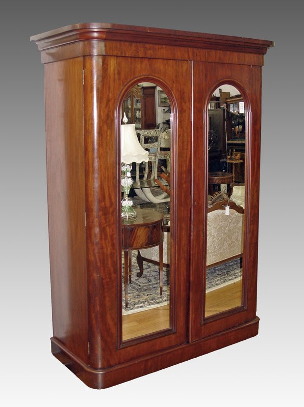 LATE 19TH C ARMOIRE WITH MIRROR FRONT DOORS: LATE 19TH C ARMOIRE WITH MIRROR FRONT DOORS: Double doors with full length arched mirror fronts. Ogee molded corners. Mahogany veneer. Interior fitted with cloths hooks on left side and slide out shel