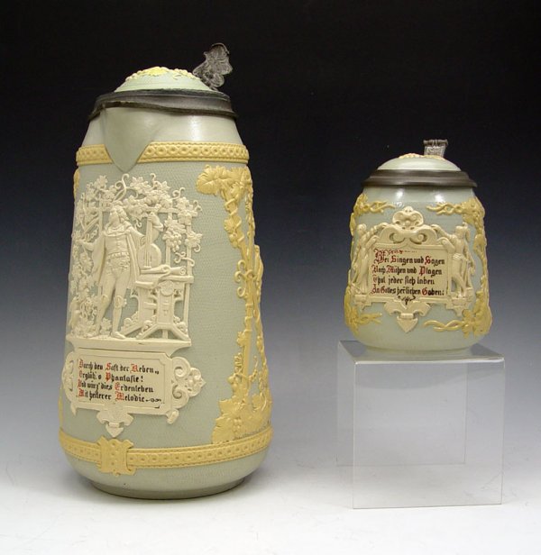 2 METTLACH RELIEF STEINS 1821 & 1370: 2 METTLACH RELIEF STEINS 1821 & 1370: To include 1) 1821 relief stein with musician and motto, trellis with grape leaf decoration. Green Villeroy & Boch Mercury stamp, incised 1821. 13" h. to thumbpre