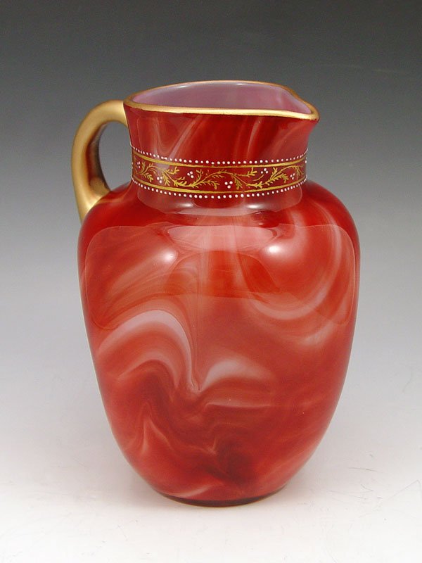 LOETZ KARNEOL MARMORIERTES ART GLASS PITCHER: LOETZ MARMORIERTES ART GLASS PITCHER: Ca. 1885-1898. Karneol (red/pink) marbled glass with gilded highlights along the neck. 8'' tall.