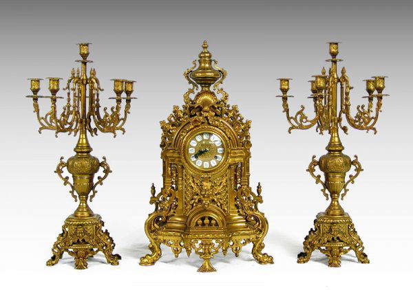 FRENCH STYLE BRASS IMPERIAL CLOCK GARNITURE SET: FRENCH STYLE BRASS IMPERIAL CLOCK GARNITURE SET: Decorative clock with cast brass body featuring North Wind face, shell, urn, and elaborate scroll designs. Marked Imperial in face, German movement. Ke