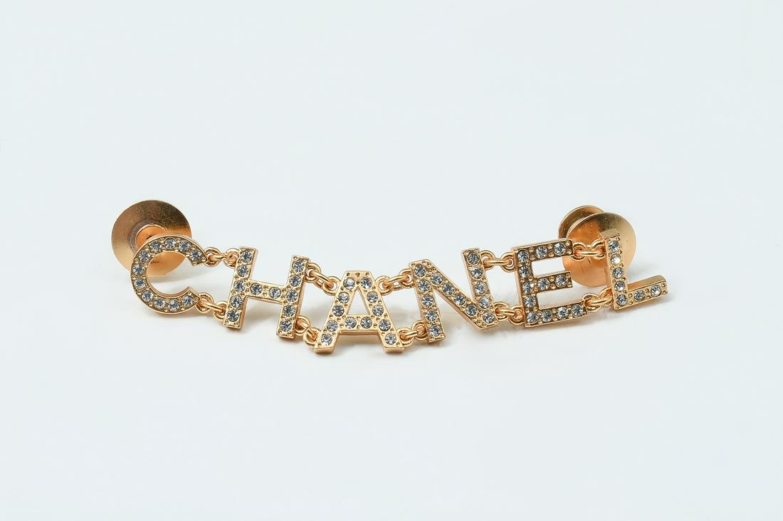 CHANEL LOGO BROOCH/PIN WITH RHINESTONES: CHANEL LOGO BROOCH/PIN WITH RHINESTONES: Wonderful, collectible CHANEL gold color brooch/pin set with rhinestones measures 2.75'' l x .375'' h. Can connect at 2 places. Stamped on back -Chanel made in