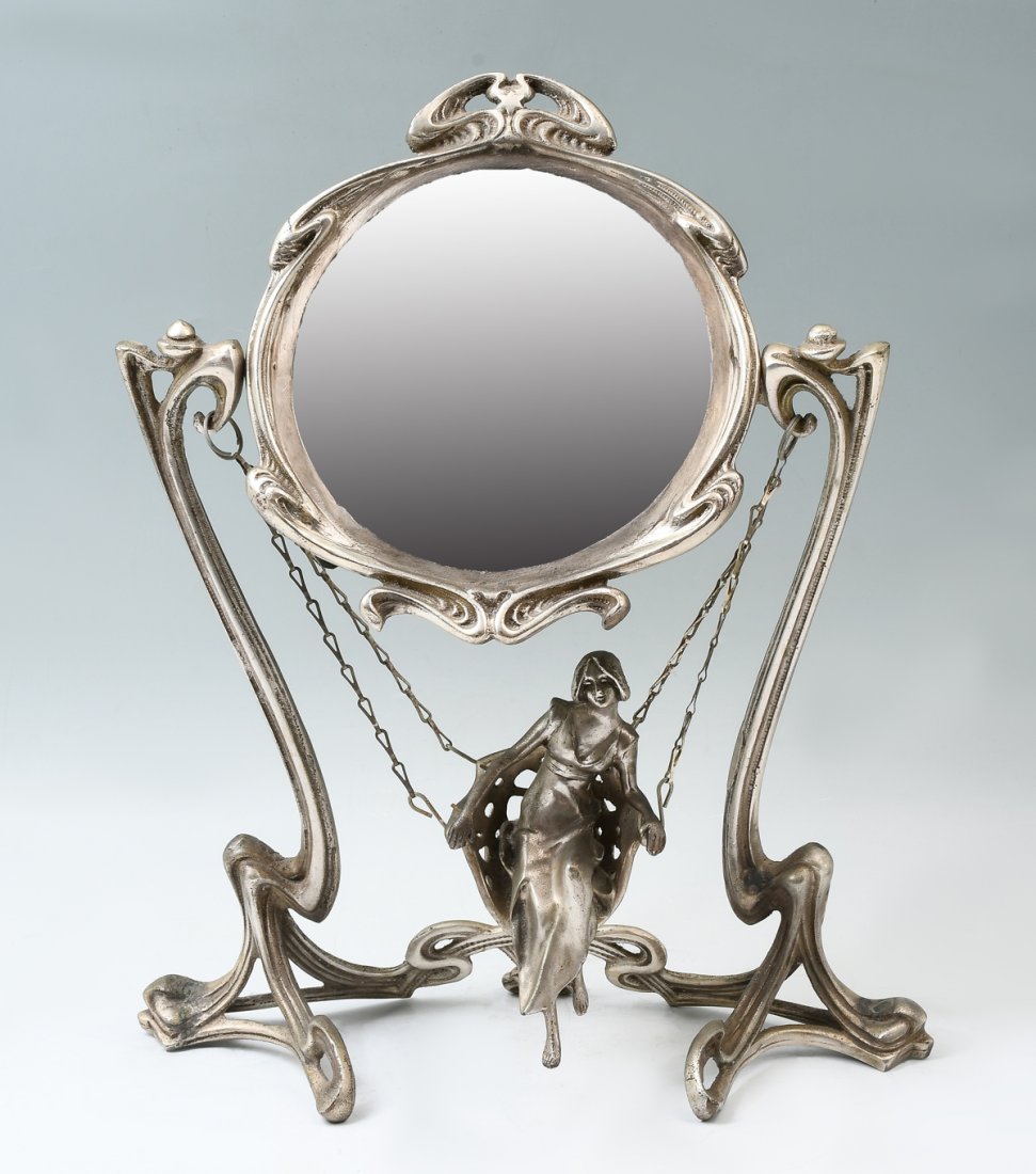 ART NOUVEAU MIRROR WITH FIGURE ON SWING: ART NOUVEAU MIRROR WITH FIGURE ON SWING: Silvered bronze Art Nouveau swiveling vanity mirror, having a female figure on a chair swing. Verso of mirror has an impressed triangle with "Erte, Paris 1907"
