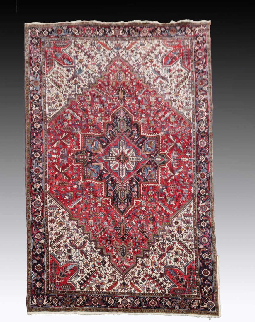 SEMI-ANTIQUE PERSIAN HERIS HAND KNOTTED WOOL RUG: SEMI-ANTIQUE PERSIAN HERIS HAND KNOTTED WOOL RUG 10'3" x 15'3":This traditional geometric based pattern rug has a large central medallion within a medallion in black, red, and ivory, on a red field th