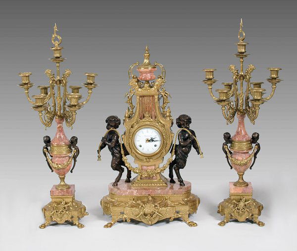 IMPERIAL FIGURAL ITALIAN CLOCK GARNITURE SET: IMPERIAL FIGURAL ITALIAN CLOCK GARNITURE SET: Gilt metal and marble featuring child pan figures holding swag, heraldic shield, rooster heads and other decoration. Marked Imperial Made in Italy on Enam