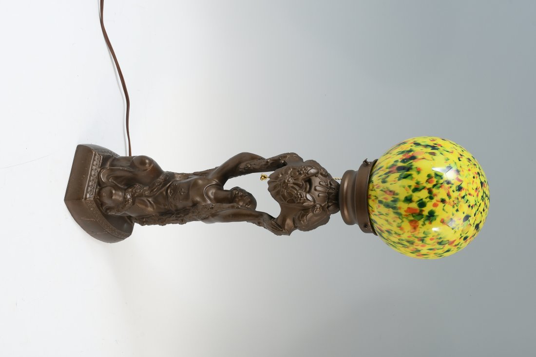 ART DECO KNEELING FIGURE LAMP: ART DECO KNEELING FIGURE LAMP: Patinated metal female form base with draping foliate, holding a Czech glass shade. Approx. 20.75" h x 5.75" l x 5.75" w.