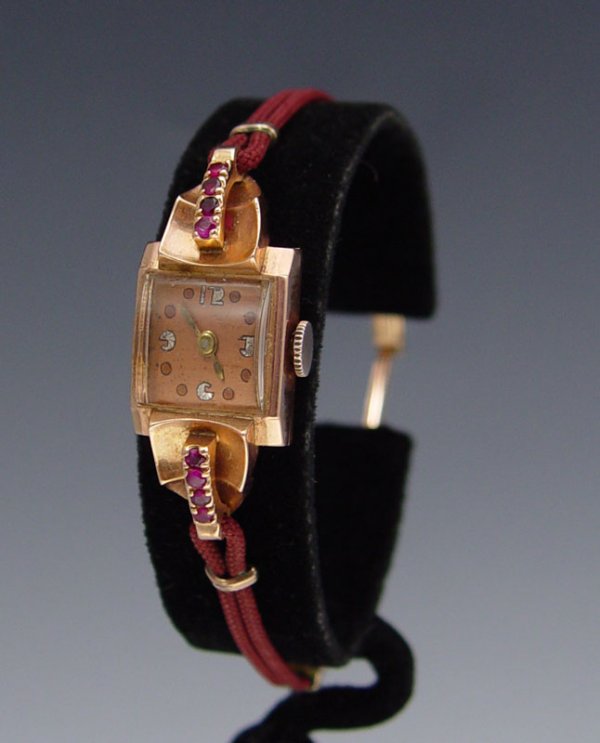CA. 1955 ART DECO 14K ROSE GOLD LADIES WATCH: LADIES 14K ROSE GOLD ART DECO WATCH WITH RUBIES: Solid 14K Art Deco watch with 17 jewel Swiss movement, in running order. 8 rubies on top bezel. Cord strap, ratchet style clasp.