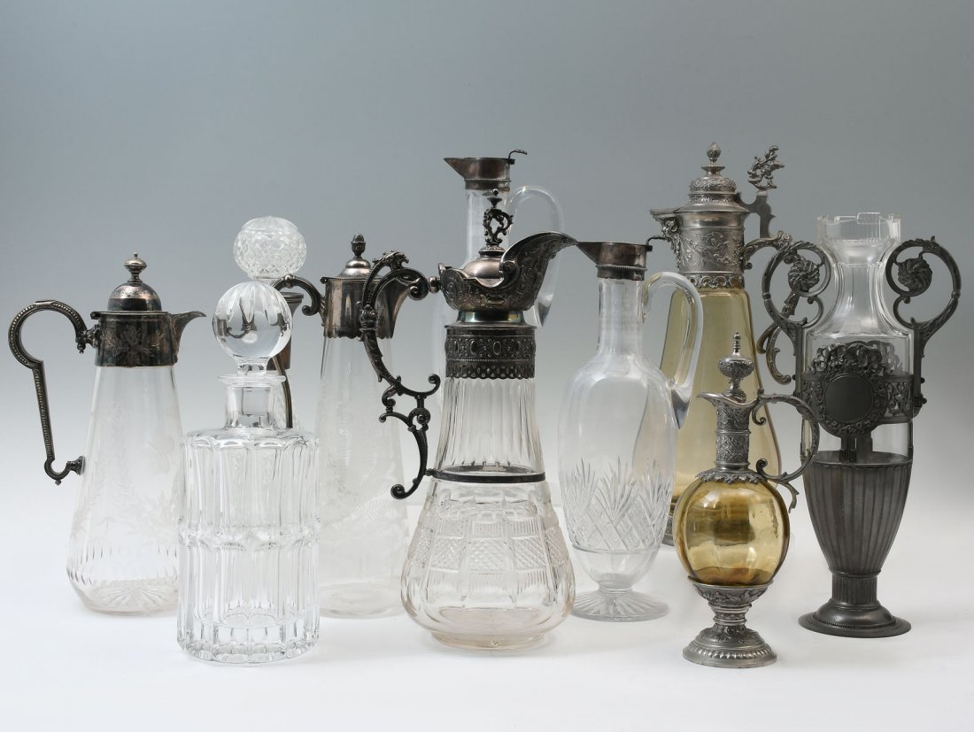 10 PC. CRYSTAL & METAL MOUNTED DECANTERS & CLARET: 10 PC. CRYSTAL & METAL MOUNTED DECANTERS & CLARET JUGS: Including continental metal & Silver mounted clarets, Ewers, decanters, & pitchers. Largest Approx. 14.25" h x 6" l x 5.25" w.