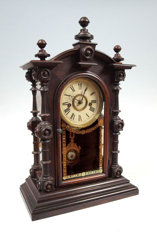 WELCH ROSEWOOD 8 DAY PATTI CLOCK: WELCH ROSEWOOD 8 DAY PATTI CLOCK: 8 day patti time and strike movement. Carved and shaped 3/4 column supports with glass on 3 sides, front glass reverse painted. Metal face, Ornate pendulum and Key in