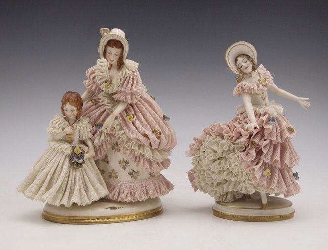 2 FURSTENBERG LACY FIGURINES: TWO FURSTENBERG LACY FIGURINES: 1) Figural group of woman with a child, 8" x 7" overall. 2) Furstenberg Single figure in pink dress and bonnet, 7 1/2" x 6".