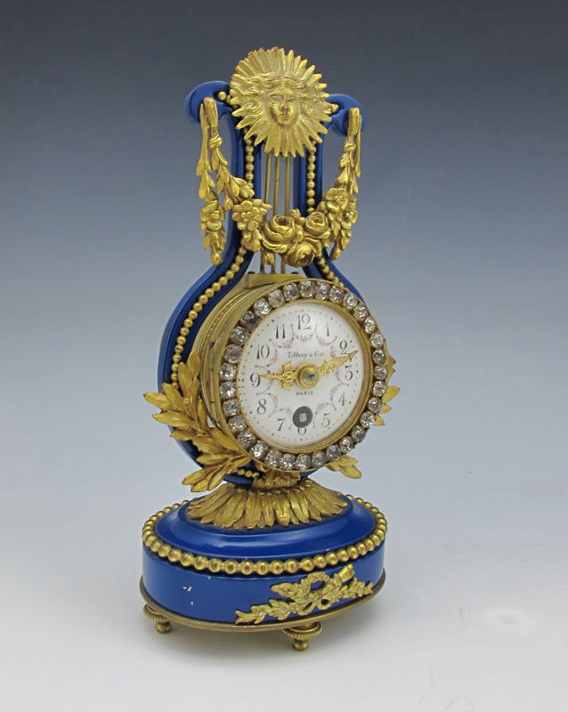FRENCH TIFFANY & CO. LYRE CLOCK: FRENCH TIFFANY & CO. LYRE CLOCK: Blue cast metal frame with applied ormolu sunburst, garland and floral decoration. Marked Tiffany & Cie on porcelain dial with painted floral swags. Key wind movement,