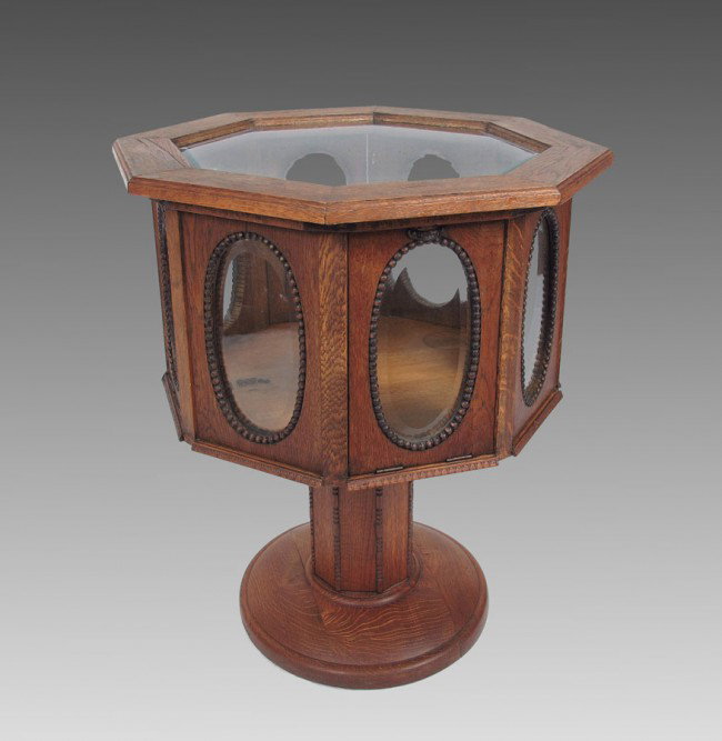 OCTAGONAL OAK DISPLAY CABINET 28'' TALL: OCTAGONAL VICTORIAN OAK VITRINE: Octagon shaped vitrine with glass top and oval beveled glass on side panels. 4 drop down doors on every other side panel. Pedestal base on round stand. 24'' wide, 24''