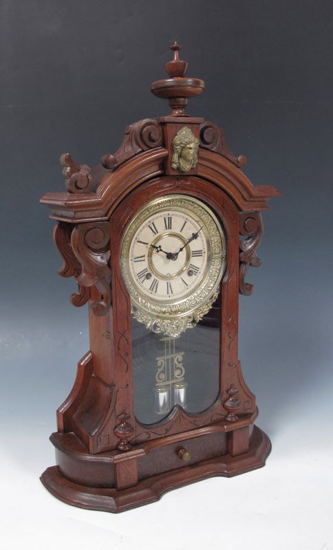 ANSONIA MONARCH BURL WALNUT MANTLE CLOCK: ANSONIA MONARCH BURL WALNUT MANTLE CLOCK: Walnut and burl walnut carved and shaped case with cast metal masqueron decoration. 8 day time & strike with pendulum, key in office. Cast metal bezel, paper 