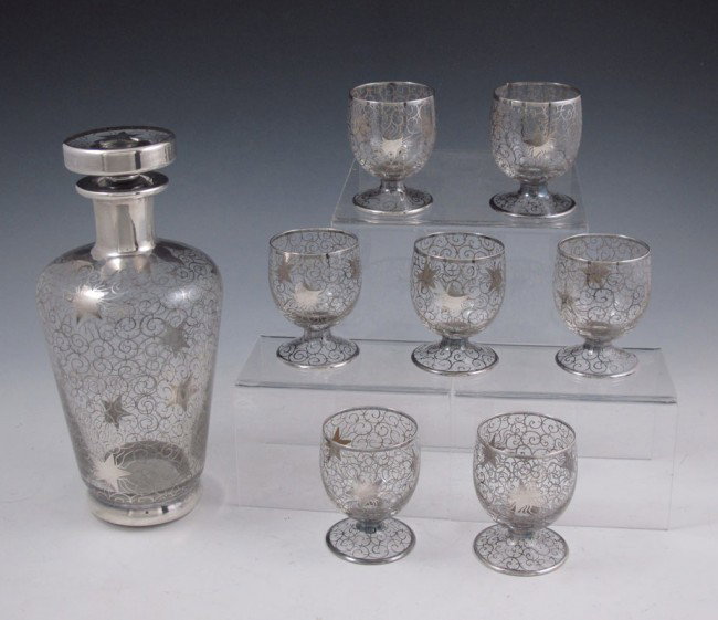 SILVER OVERLAY LIQUOR SET: SILVER OVERLAY LIQUOR SET: Illegibly signed decanter with etched number 174 on base. Sold with 7 cordials with matching design. Unmarked as to silver fineness. Decanter 8 3/4" h. x 4" dia., cordials 2
