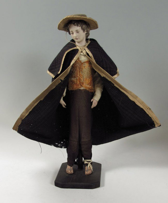 FRENCH WOOD DOLL OR POSSIBLY CRECHE FIGURE: FRENCH WOOD DOLL OR POSSIBLY CRECHE FIGURE: Ceramic head with composition hands and feet. Fragmented silk brocade vest and hand made silk and wool hat. Comes with removable cloak. 27 1/2" h. x 8" x 9 