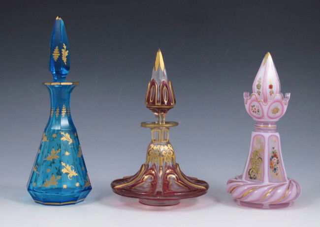 GROUP OF 3 BOHEMIAN GLASS PERFUME BOTTLES: GROUP OF 3 BOHEMIAN GLASS PERFUME BOTTLES: 1) Pink opaline with hand enameling, 6" tall. 2) Cranberry and clear glass with hand gilding, 6". 3) Blue glass with gold designs, 7" tall.