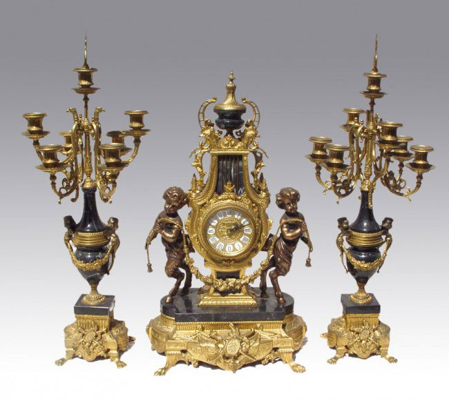 IMPERIAL FIGURAL CLOCK GARNITURE SET: IMPERIAL FIGURAL CLOCK GARNITURE SET: Figural pan children, cast metal body with black variegated marble accents. Battery operated quartz movement. 24" h. x 14" x 8". Sold with pair of matching 7 ligh