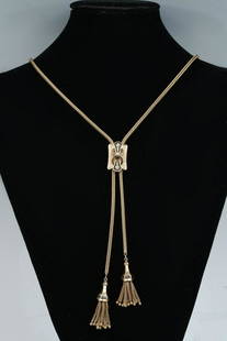 MID CENTURY VICTORIAN 14K TASSEL SLIDE NECKLACE: MID CENTURY VICTORIAN 14K TASSEL SLIDE NECKLACE: 1940s 14K yellow gold sautoir necklace features 14K yellow gold cartouche shaped slide accented with a single diamond and black enamel; slide measures