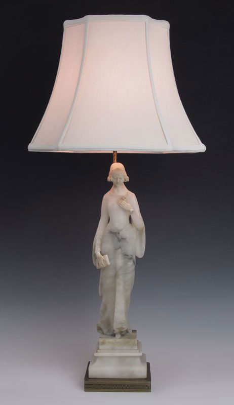 CARVED FIGURAL WOMAN ALABASTER LAMP: CARVED FIGURAL WOMAN ALABASTER LAMP: Figural woman with holding rose and book, on metal base. 33 1/2 h. x 6" x 6". Sold with cloth shade, 12" h. x 15 1/4" x 12 1/2".