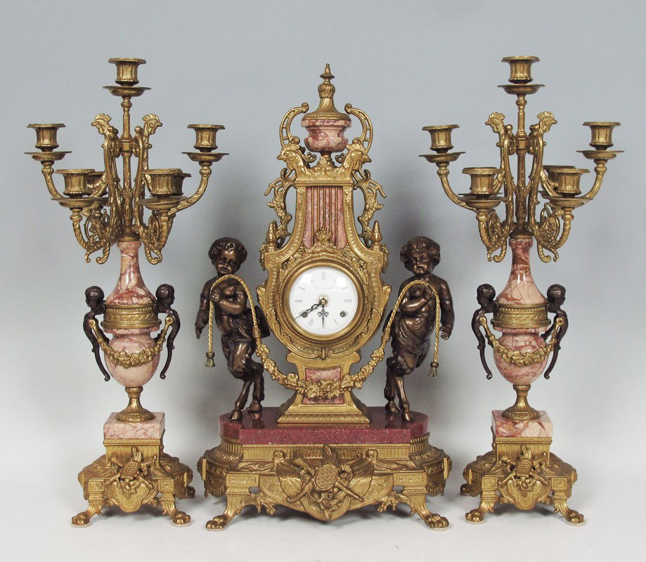 IMPERIAL FIGURAL CLOCK GARNITURE SET: IMPERIAL FIGURAL CLOCK GARNITURE SET: Figural pan children, cast metal body with pink variegated marble accents. Key wind time & strike movement. 24" h. x 14" x 8". Sold with pair of matching 7 light 