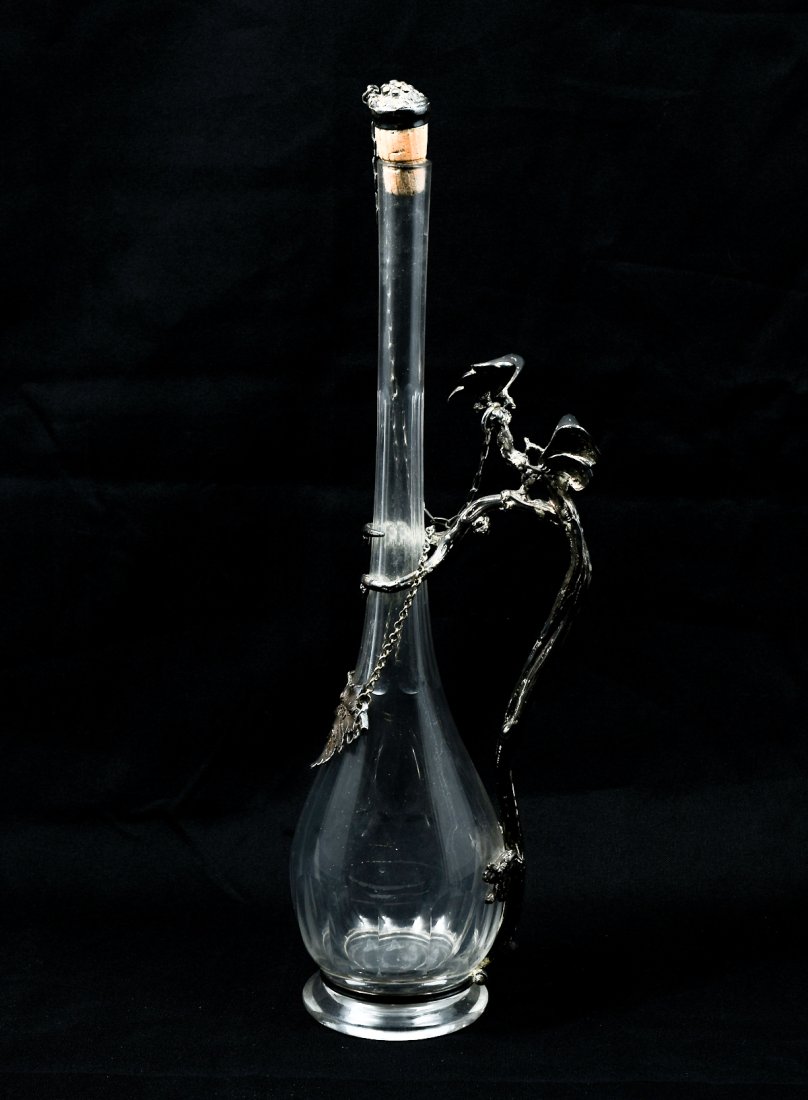 EARLY 20TH-CENTURY METAL MOUNTED WINE DECANTER: EARLY 20TH-CENTURY METAL MOUNTED WINE DECANTER: Glass and Silvered metal mounted Wine Decanter, early 20th-century, bottle shape with a LONG faceted neck. Applied metal Tree form handle with Butterfli