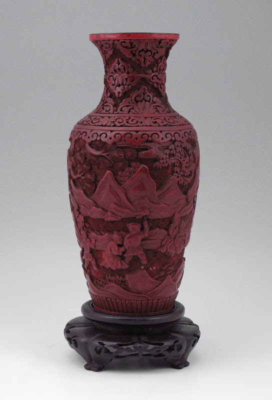 CINNABAR VASE: CINNABAR VASE: Carved landscape with figures. Base has been removed for lamp conversion. 9 3" h. x 4 1/2". Sold with carved wood base, hole in center for cord. 2" h. x 5".