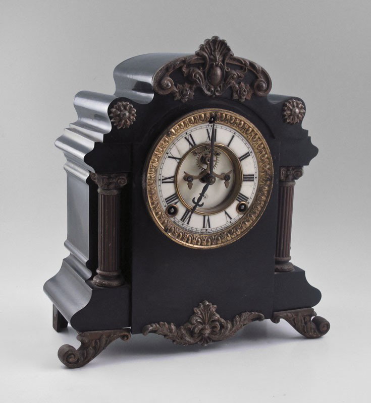 CAST METAL ANSONIA MANTLE CLOCK: CAST METAL ANSONIA MANTLE CLOCK: Cast metal case applied decoration and full column supports. Porcelain face with open escapement, Roman numerals. Time and strike movement marked Ansonia. Key and pend
