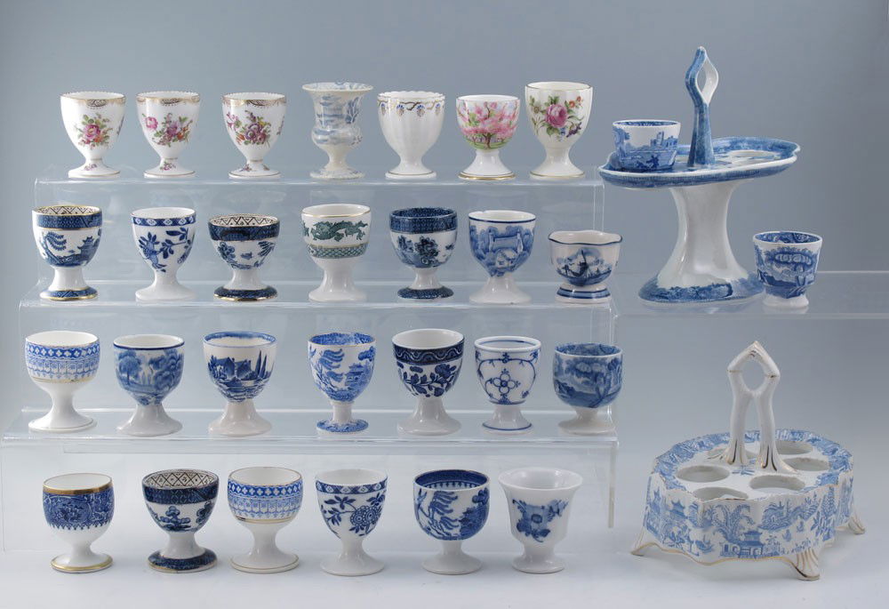 33 EGG CUPS & 2 STAFFORDSHIRE EGG STANDS: 33 PIECE COLLECTION EGG CUPS AND TWO STAFFORDSHIRE EGG STANDS: To include Booths Blue Willow, Coalport, Tenby, Mintons Blue Willow, Doulton Clifton, Spodes Italian, Royal Albert Blossom Time, hand pai