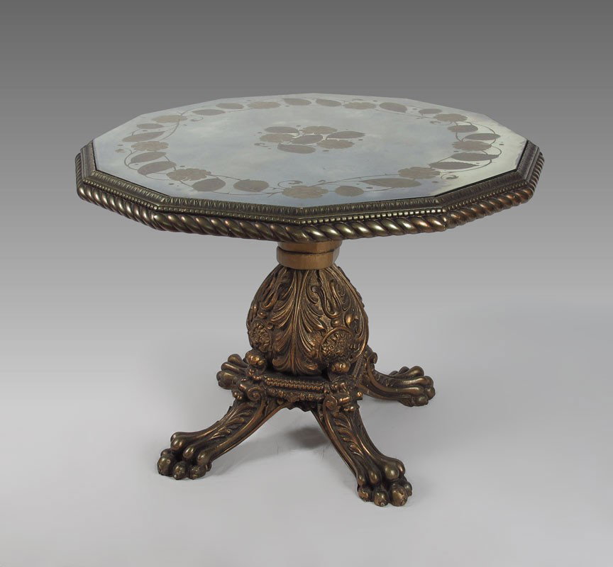 EGLOMISE MIRROR TOP PEDESTAL TABLE: EGLOMISE MIRROR TOP PEDESTAL TABLE: Gilt wood table of exaggerated carvings to the pedestal and paw feet. 30" h. x 43" dia.