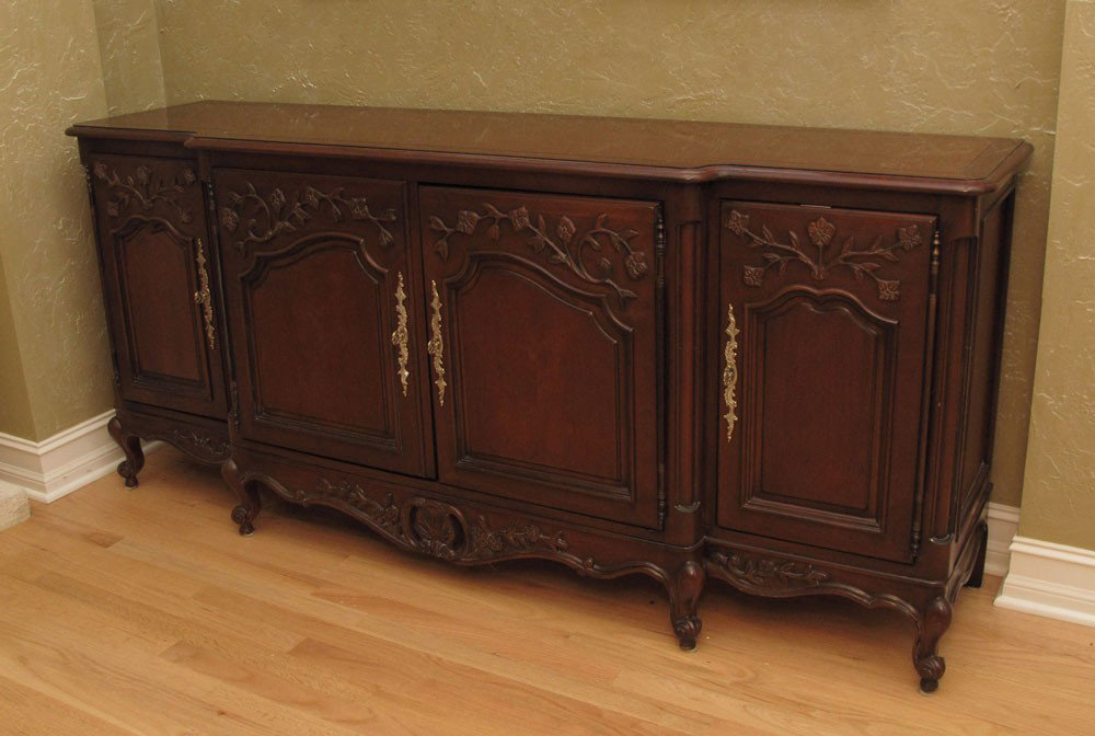 CENTURY FURNITURE CARVED SIDEBOARD: CENTURY FURNITURE CARVED SIDEBOARD: Shaped top over 4 floral design carved doors with ornate brass escutcheons, carved and shaped skirt and 4 carved front legs. 32 1/2" x 73 1/4" x 19".