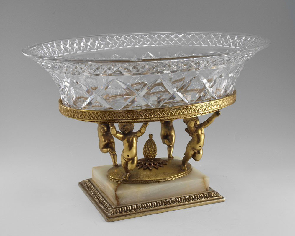 PAIRPOINT METAL MOUNTED CRYSTAL BOWL: PAIRPOINT METAL MOUNTED CRYSTAL BOWL: Oval crystal bowl supported by a gilt metal base of 4 cherubs, onyx plinth. Signed Pairpoint. 8 1/2" x 13 1/4".