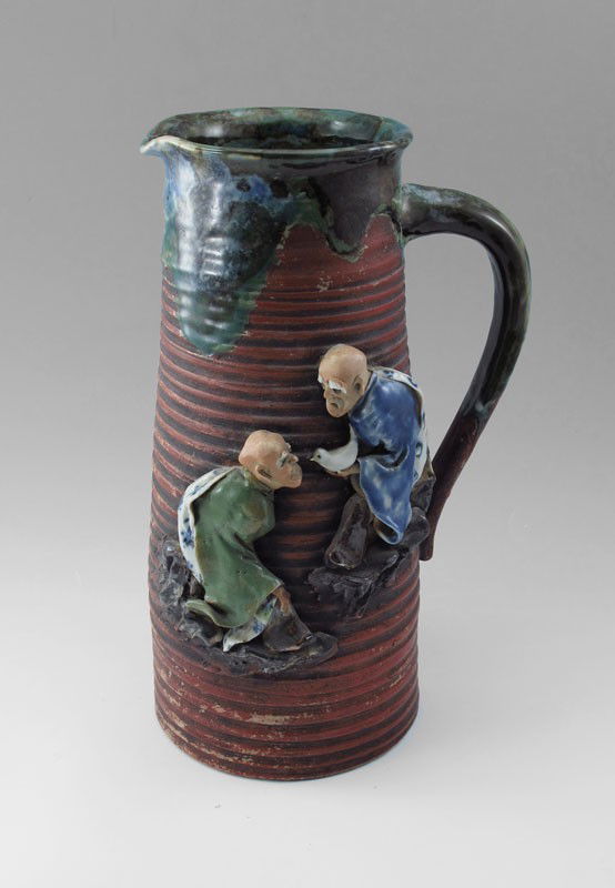JAPANESE SUMIDA GAWA POTTERY PITCHER 12.5'' TALL: JAPANESE SUMIDA GAWA EARTHENWARE POTTERY TALL PITCHER: Decorated with two figures, signed on cartouch in blue underglaze. 12 1/2'' h