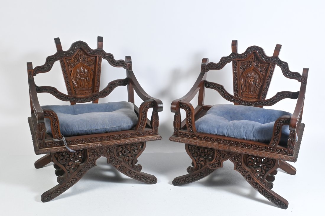 PAIR OF CARVED THAI ARMCHAIRS: PAIR OF CARVED THAI ARMCHAIRS: Two solid wood, profusely carved Howdah chairs. Also known as elephant saddle-seat chairs, these feature intricate floral carvings all around. Backrests displaying three