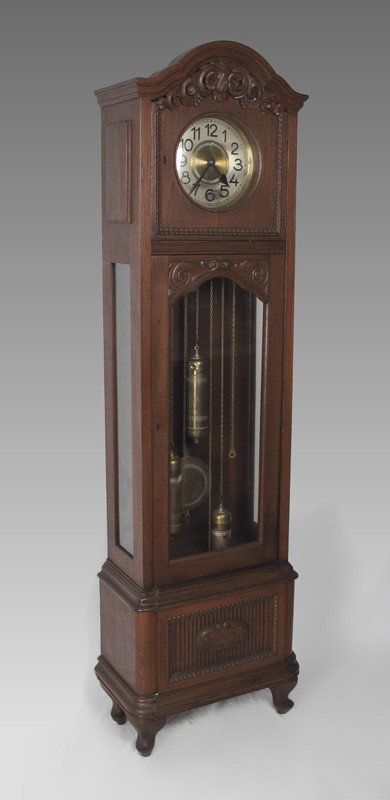 GERMAN DECO CARVED GRANDFATHER CLOCK: GERMAN DECO CARVED GRANDFATHER CLOCK: Walnut case with applied carved decoration. Mixed metal face with triple weight time and strike movement. 81 1/2" h. x 21 1/4" x 12".