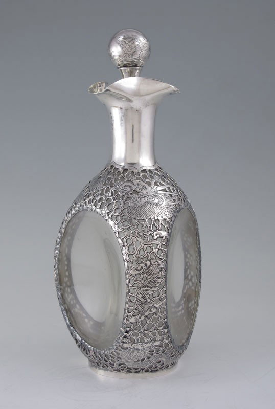 ORIENTAL DRAGON MOTIF SILVER OVERLAY DECANTER: ORIENTAL DRAGON MOTIF SILVER OVERLAY DECANTER: Clear glass with filigree and dragon motif silver overlay. Marked on base Kai Kee 90 Silver, glass marked A 660, Haigs UGB. Engraved dragon motif stopper