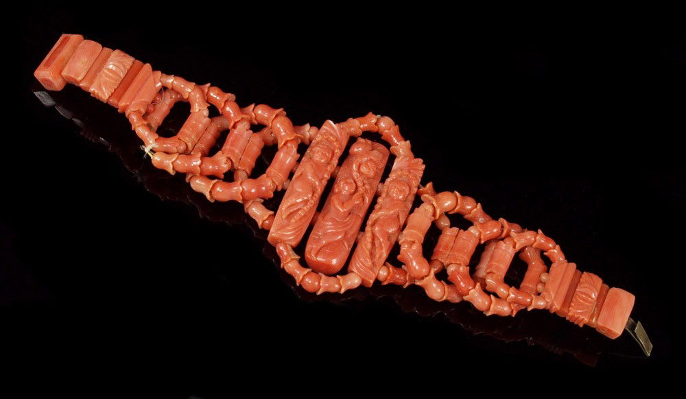 CARVED CORAL BRACELET: CARVED CORAL BRACELET: Floriform and round beads woven in rings to create bracelet, centered by three panels carved with cherubs and female figure, approx. 6 1/2".