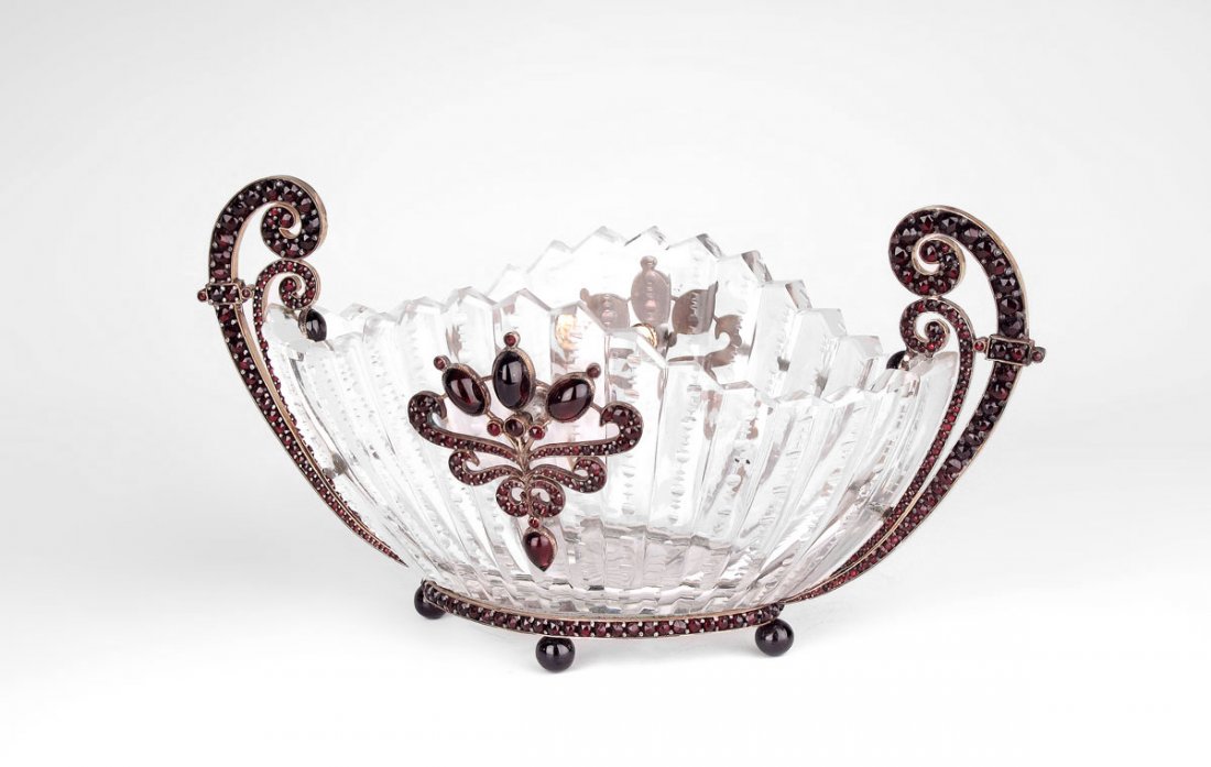 GOLD AND GARNET MOUNTED CRYSTAL BOWL: GOLD AND GARNET MOUNTED CRYSTAL BOWL: Zipper cut glass dish with garnets in 10K gold mounts, ball feet. Illegible hallmarks to the gold, assayed at 10K. 3.5''h. x 7''l.
