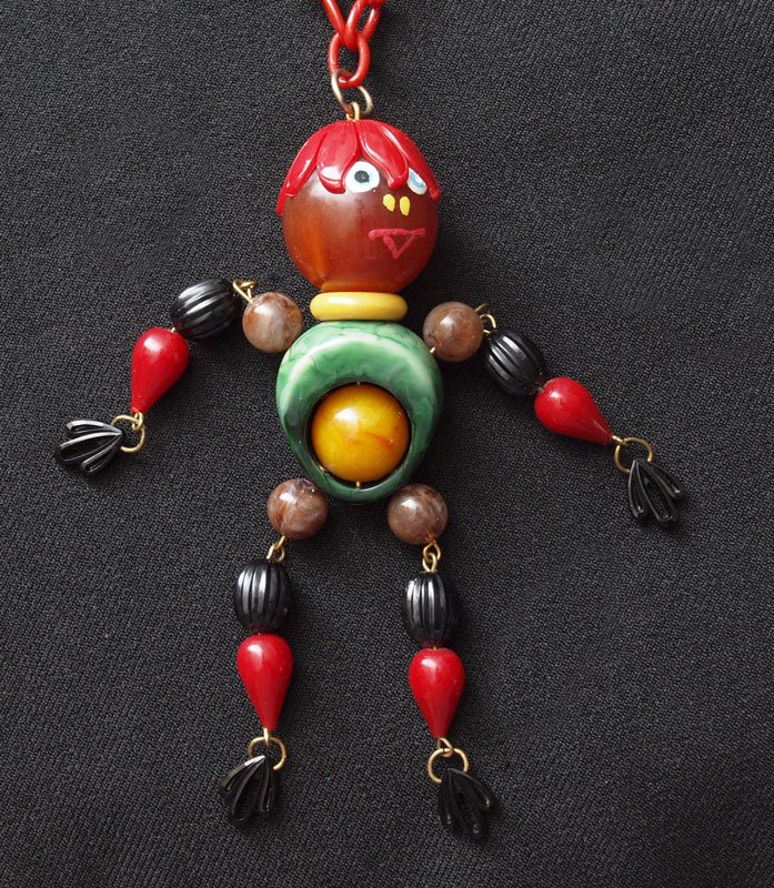 FIGURAL BAKELITE AND PLASTIC CRIB TOY NECKLACE: FIGURAL BAKELITE AND PLASTIC CRIB TOY NECKLACE: 8 color whimsy figure, 4.5'', hangs from an approx. 27'' red chain.
